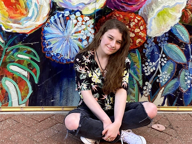 Marcie Schroeder sitting in front of a flower mural