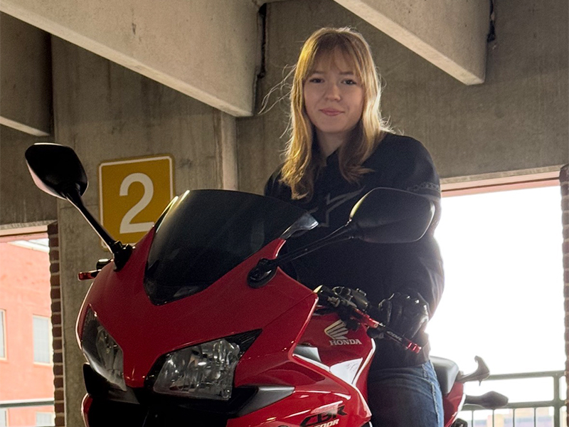 Photo of Bethany Johnson on a bright red motorcycle.