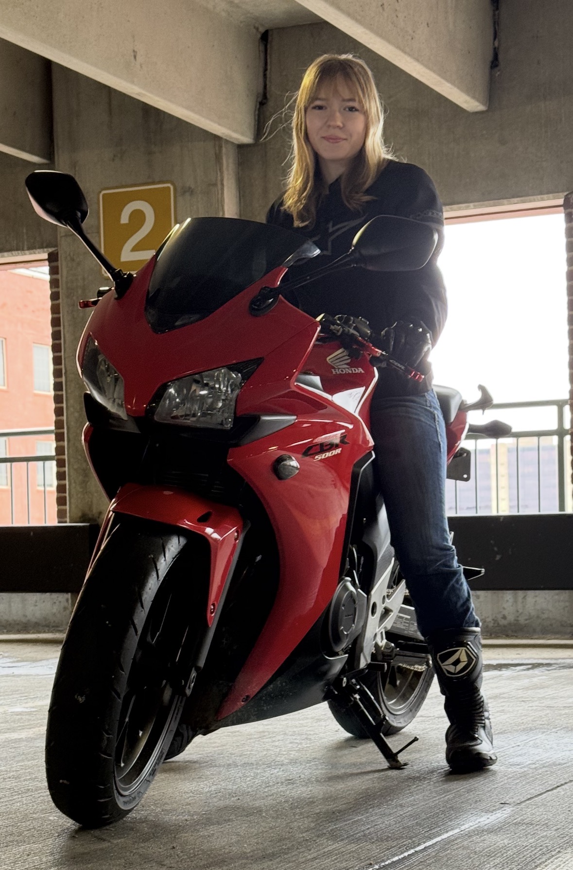 Photo of Bethany Johnson on a bright red motorcycle.