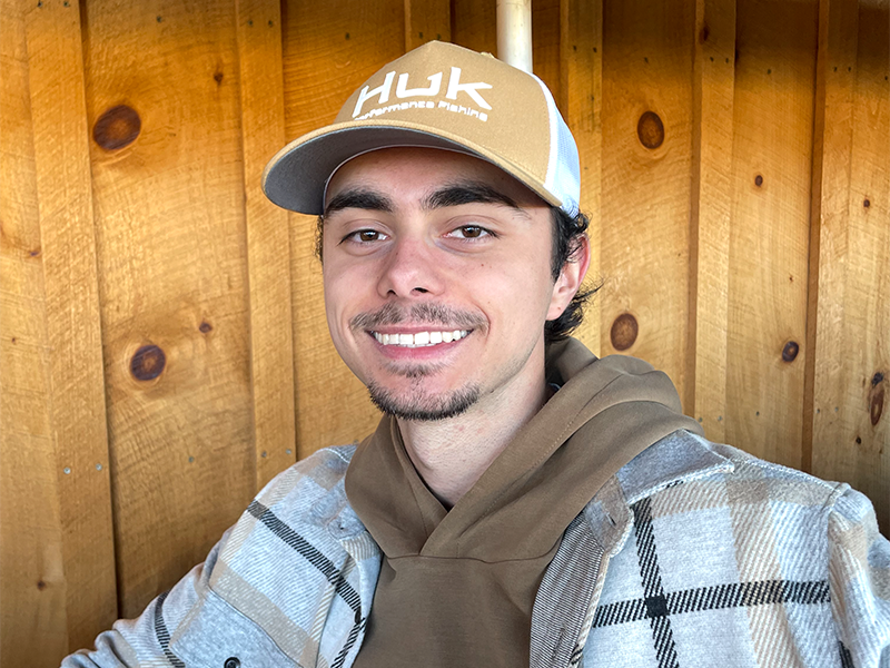 Photo of Layne Graves in casual clothing in front of a wooden door.