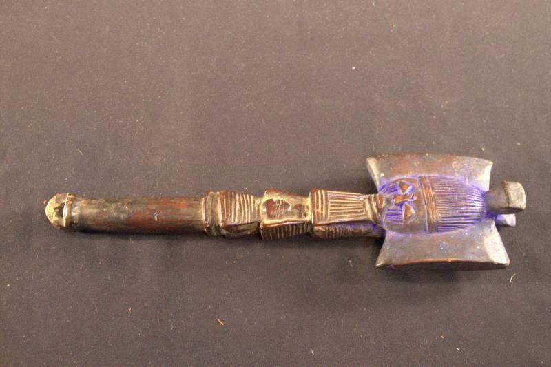 Dance wand with a face carved at the top and dyed blue.