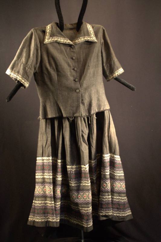 Grey jacket and skirt with geometric design on the bottom portion of the skirt.