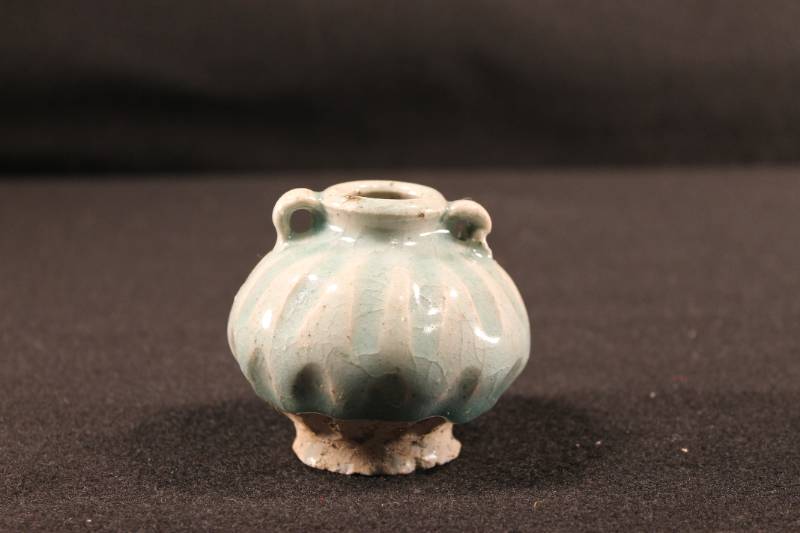 Small Annamese celadon jarlet that is a ribbed melon shape and finished with two jug handles on a slightly raised lip. Top two-thirds of the body is glazed with a blue/green celadon. Botton third is unglazed.