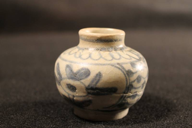 Blue and white bulbous-shaped ceramic jarlet. Decorated with floral flourishes. medium-sized mouth with raised lip.
