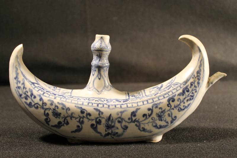 Small oil lamp in shape of a boat. Cobalt blue decoration. The top has an extended wick spout. Furthest point has been chipped off.