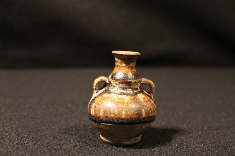Small brown gourd-shaped flask with an everted mouth-rim and two ring-handles on the shoulders; with a deep caramel-colored glaze.
