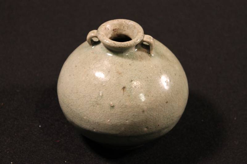 Small, bulbous-shaped, gray-green jar finished at the shoulders with small lug handles.