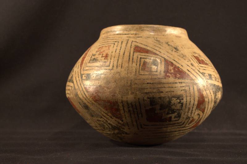 Jar decorated with a stepped triangle geometric design. The red and black paint making up the design is heavily worn.