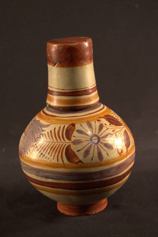 Water jar and cup are colored cream with orange, red and purple stripes and flowers for decoration. The cup is placed on the top of the water jar like a lid.