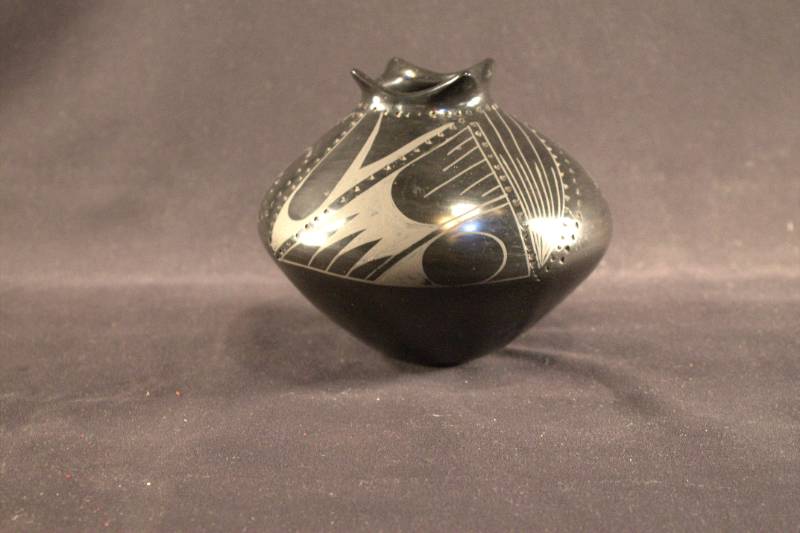 Black jar with geometric designs on the top half.