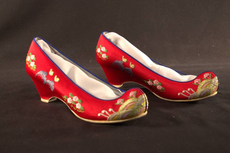 Red shoes with embroidered flower designs of white, pink, yellow, purple, blue and gold. 