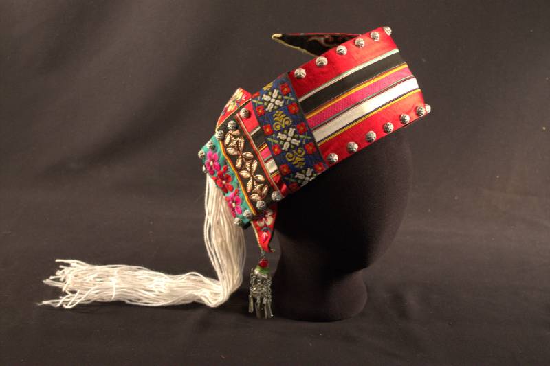 Hat is open in back, has silver beading and multi-colored flowers, yarn hanging from back, and built-in "earrings".