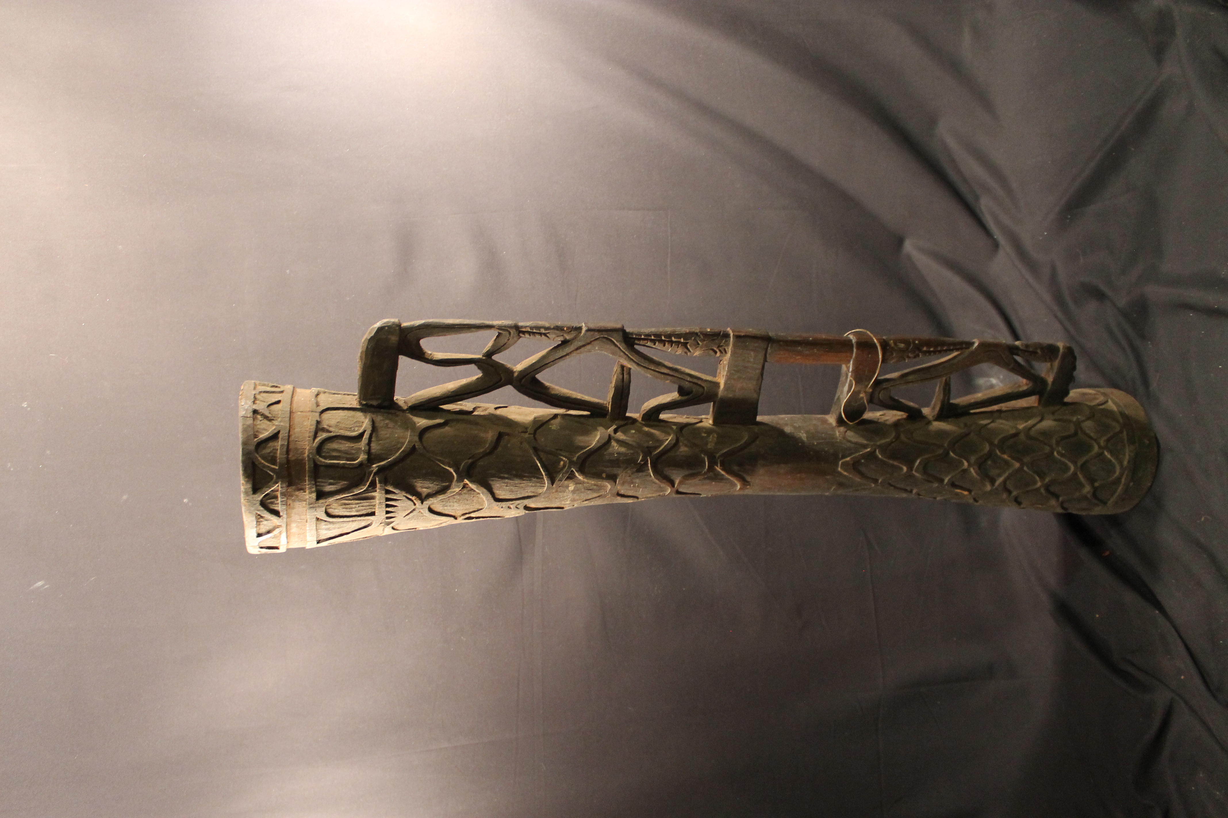 Carved wooden drum which has a handle with a hornbill and snake design.