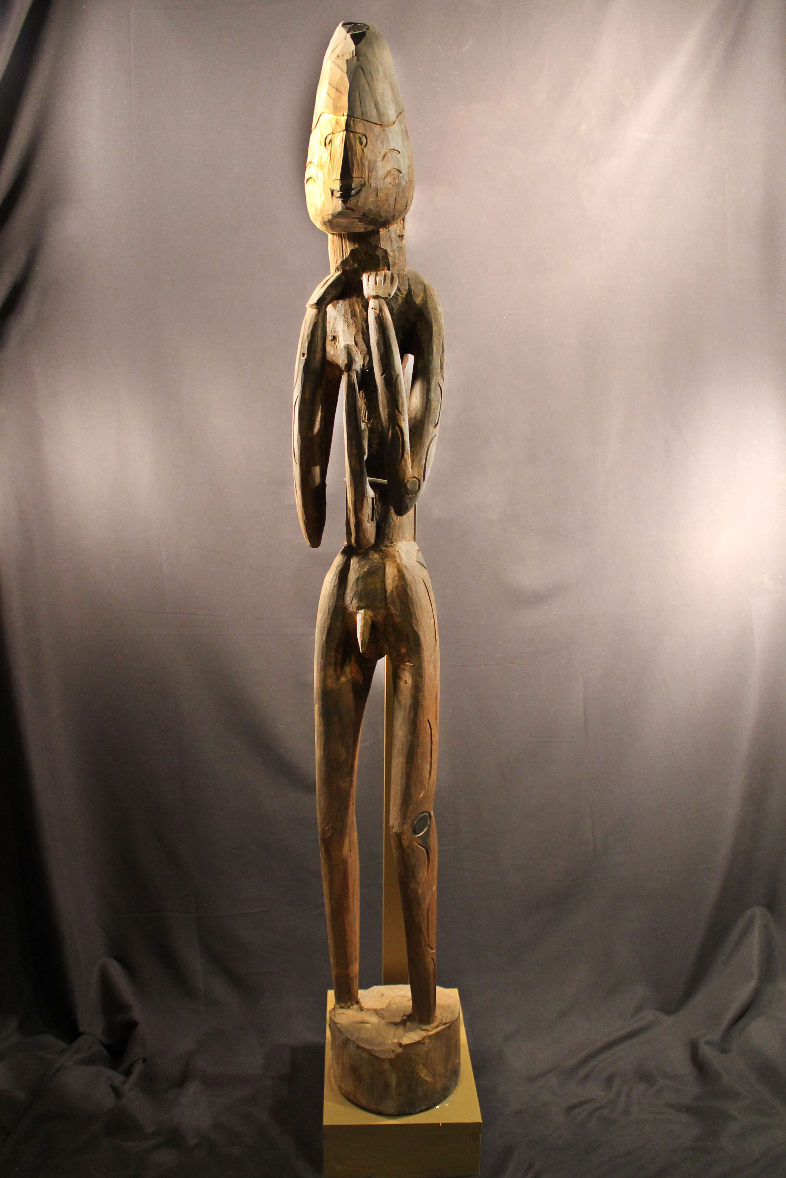 Carved wooden male ancestor. Its hands are on its neck and has a hornbill bird’s head on the chest