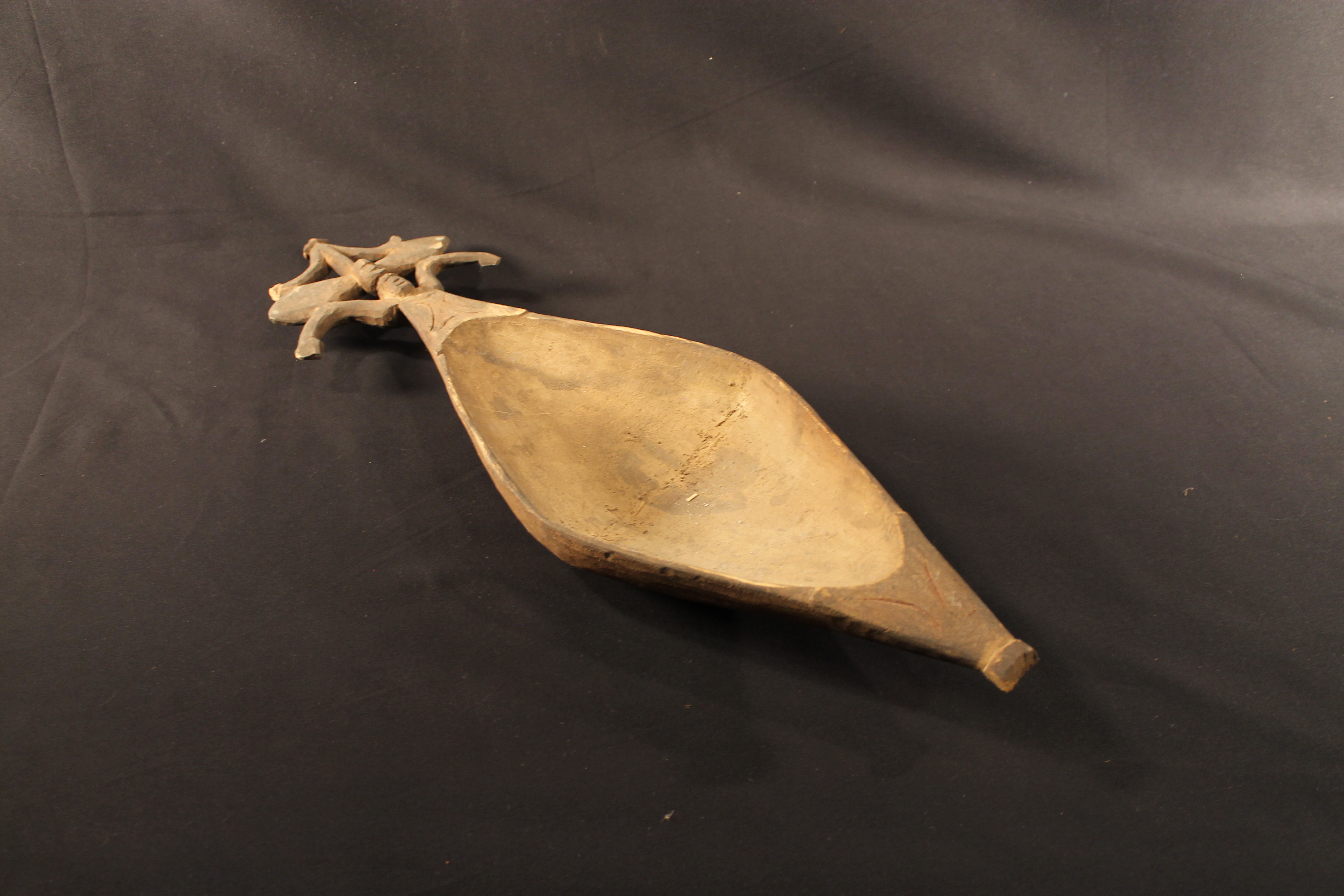 Carved wooden bowl in the shape of a diamond with a decorated sago palm design on top.