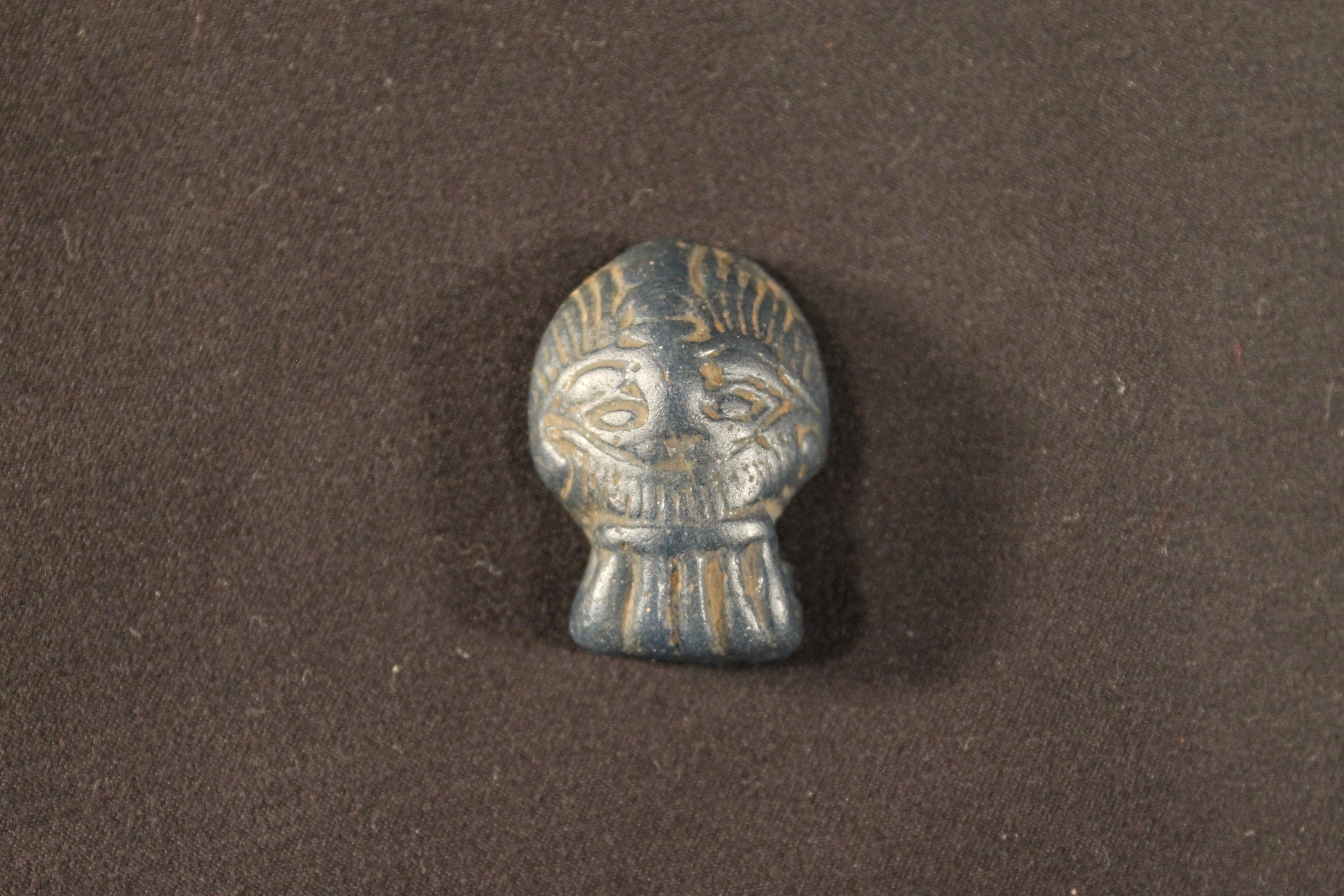Black stone carved into the shape of a human male face.