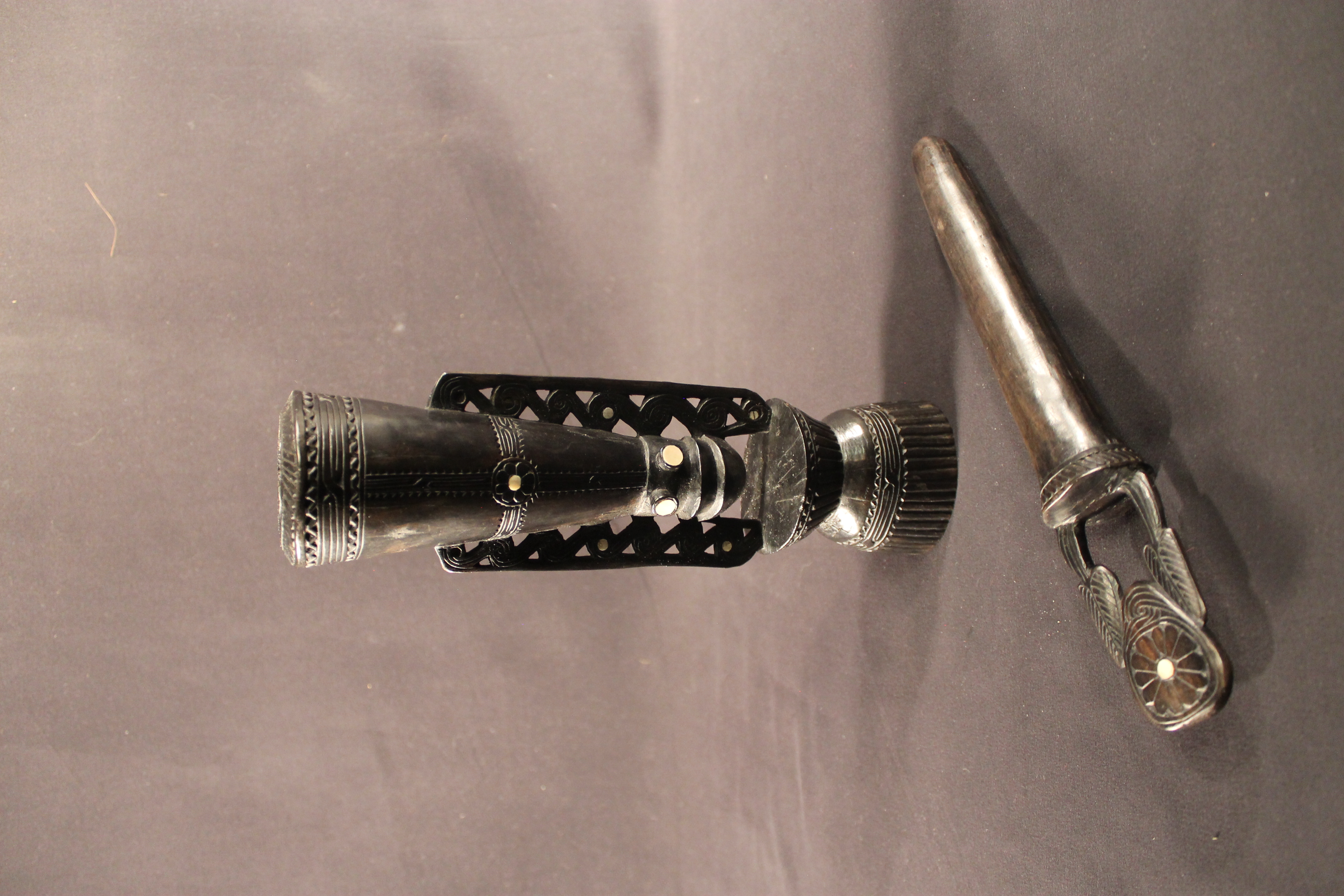 Mortar and pestle made of dark carved wood. Mortar featured a face design in the cente