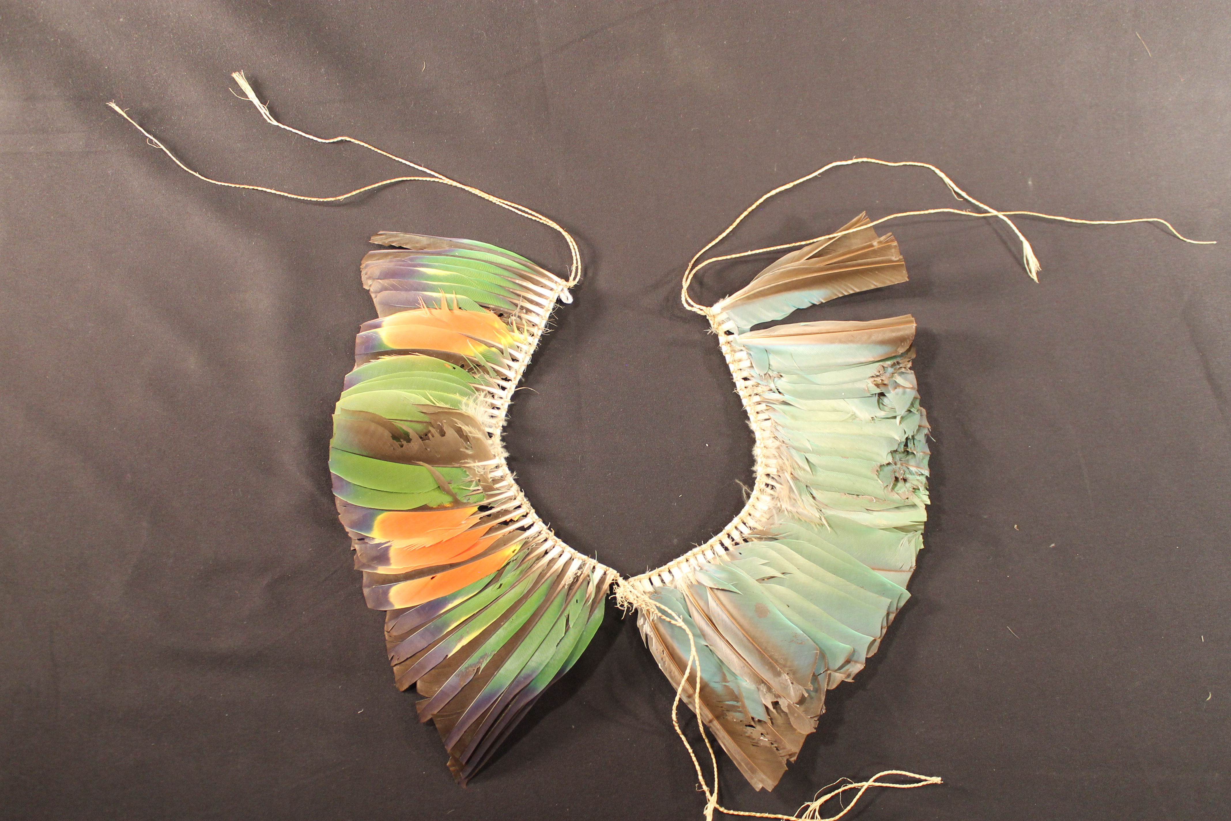 Band of multi-colored feathers tied at the base on a long string. Most feathers are green at the base then it changes to yellow and red feathers that have blue or black tips.