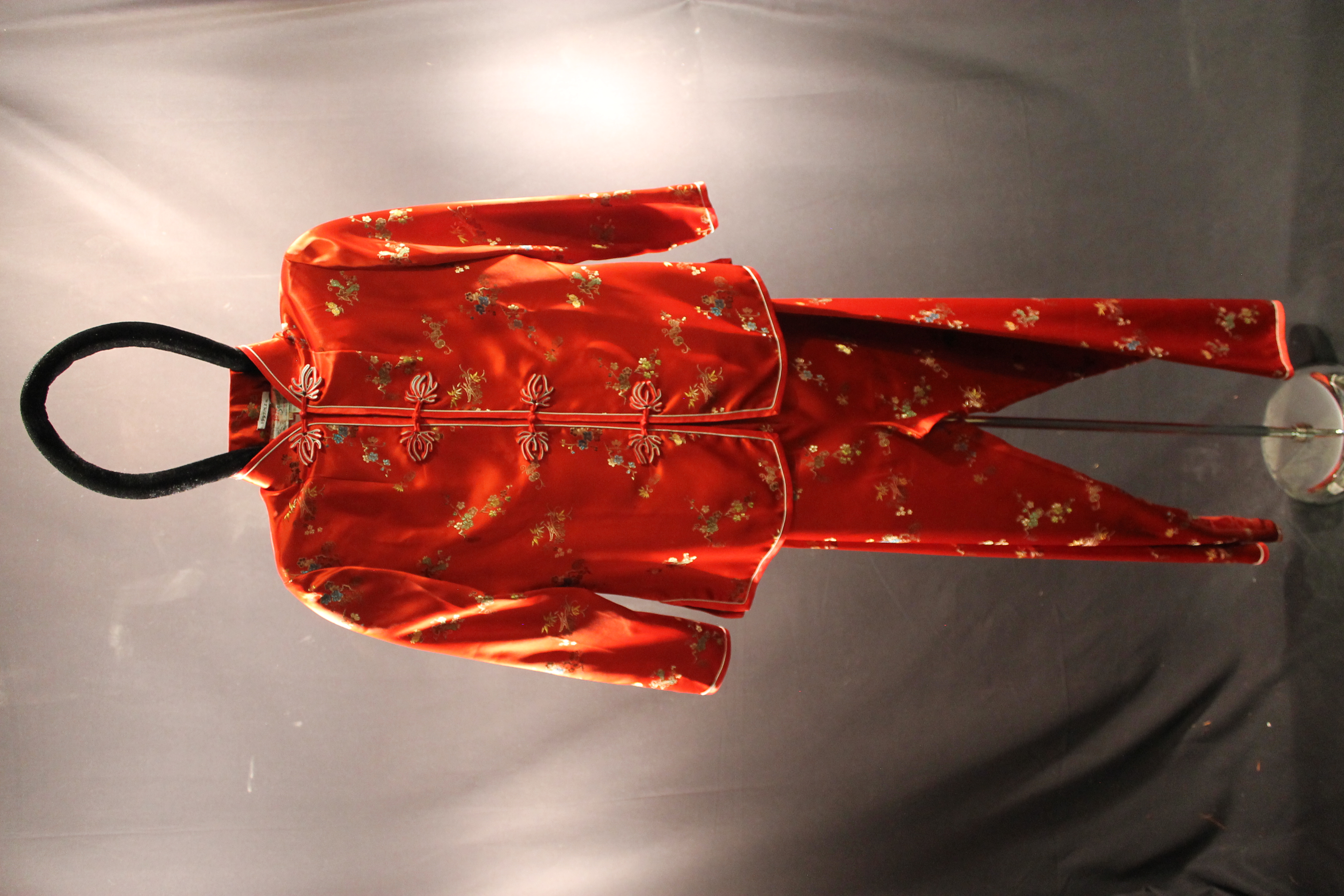 Red silk jacket with small flower designs. On the bottom is red silk pants with small flower designs.