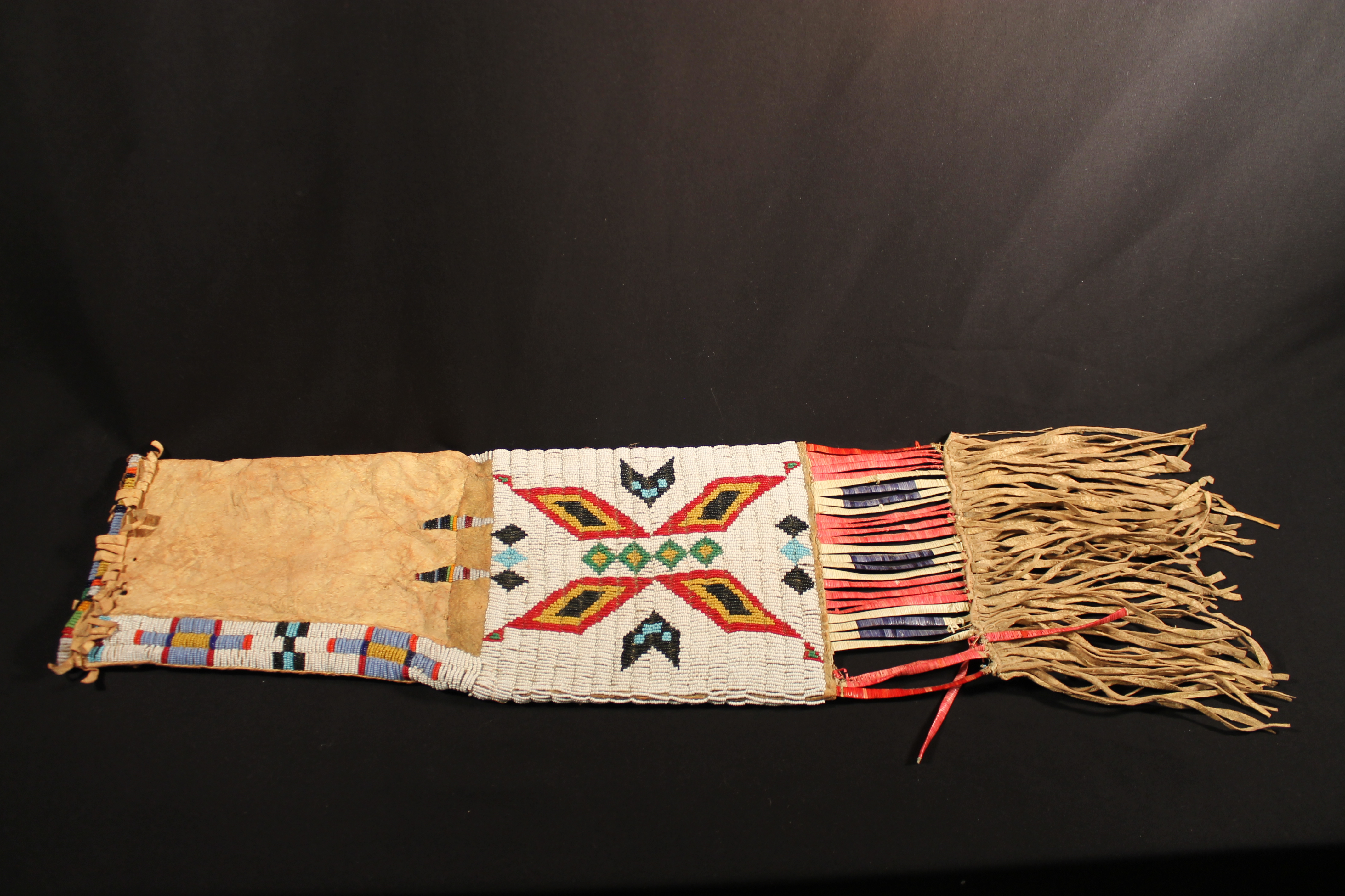 Long, narrow leather pipe bag decorated with multi-coloured beads and fringe on bottom.