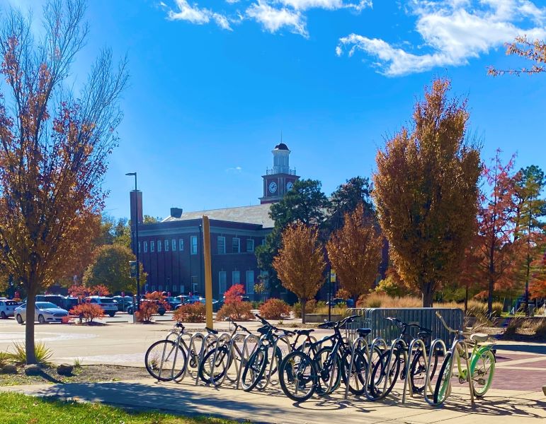 Bikes in front of Morrison Hall with fall trees.