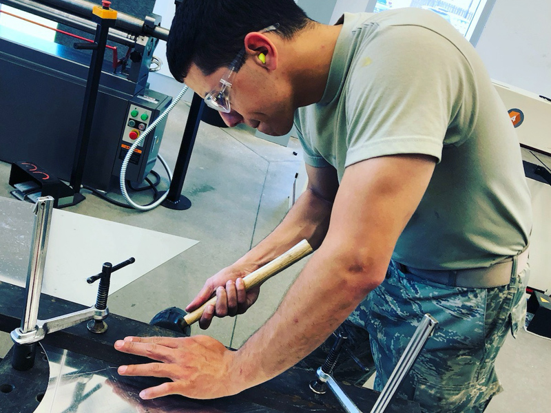 Male with rubber mallet at work bench