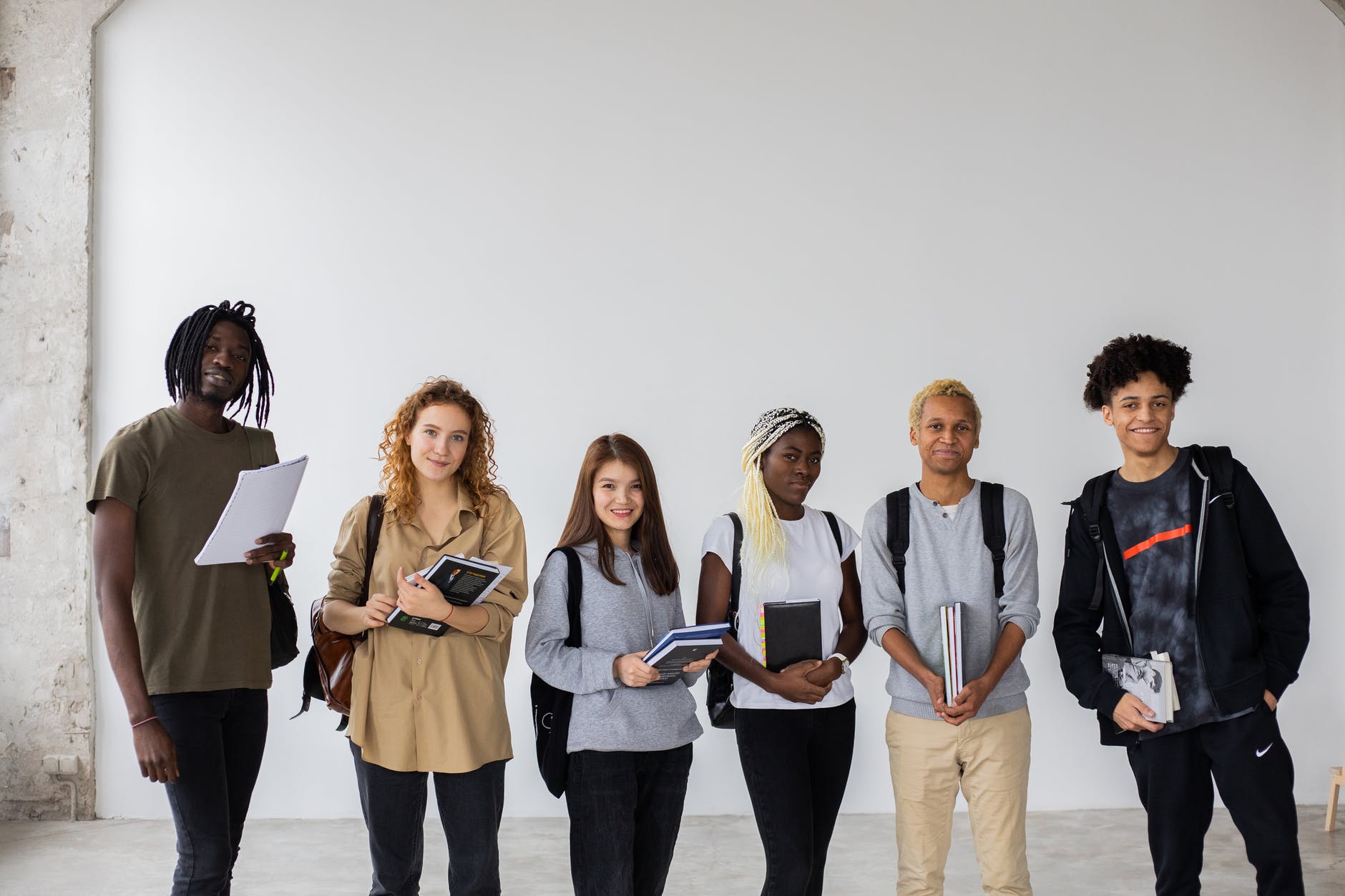 A group of international students holding books and standing side by side