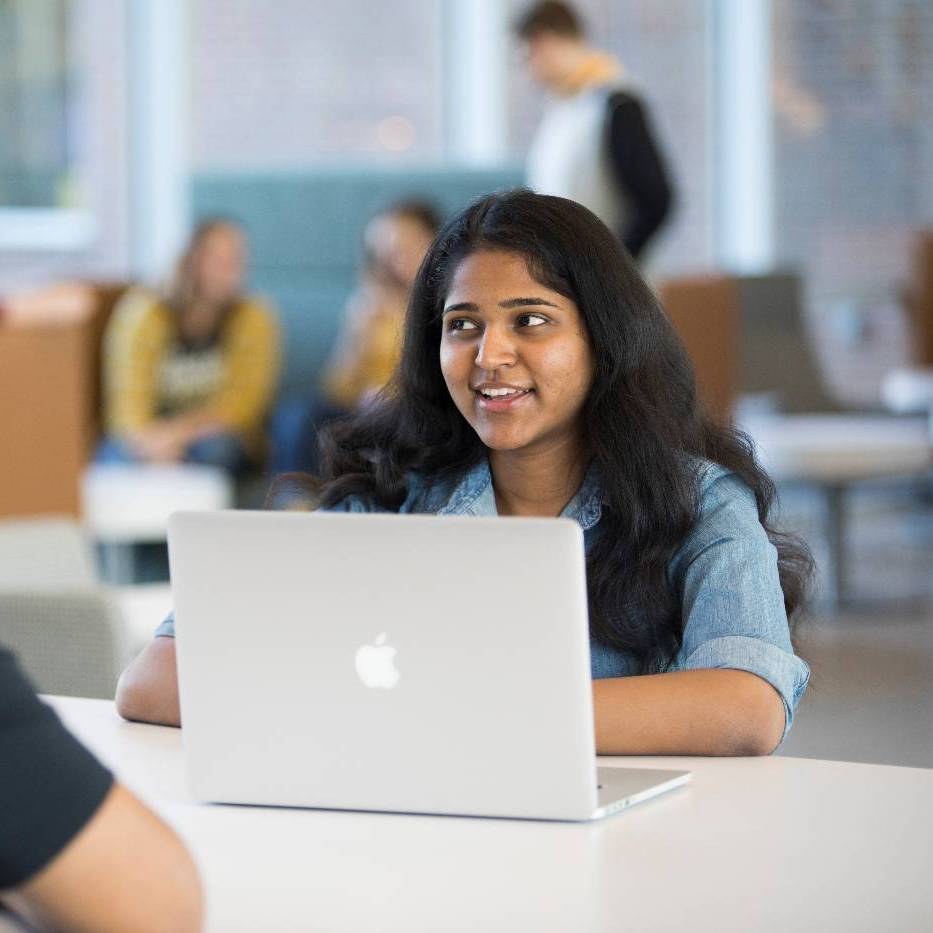 Female student smiling while working on laptop