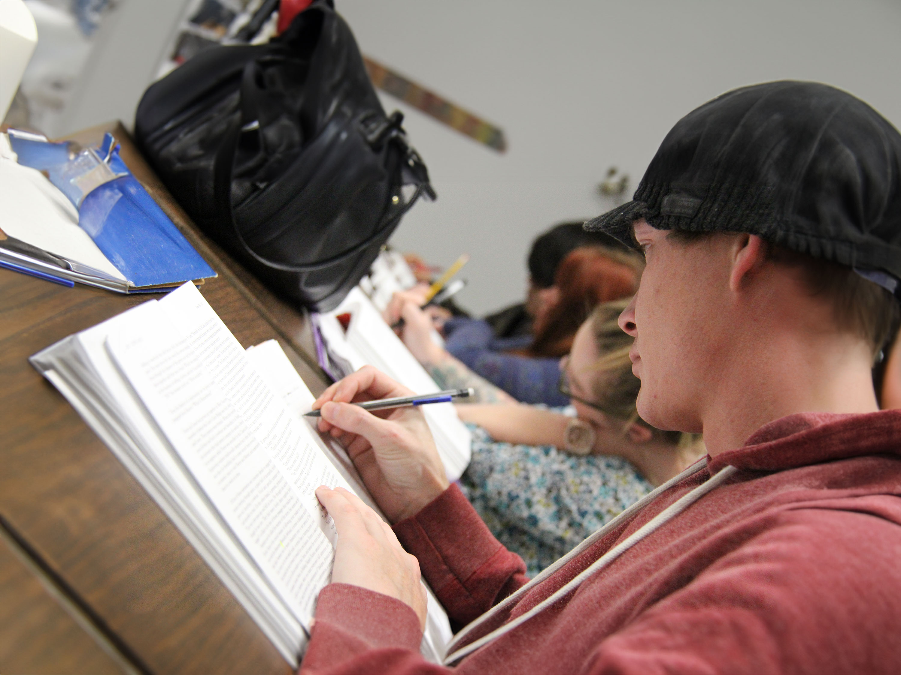 Student writing on a piece of paper with their book open.