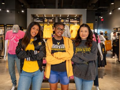 Three students standing at the Shocker Store in shocker gear