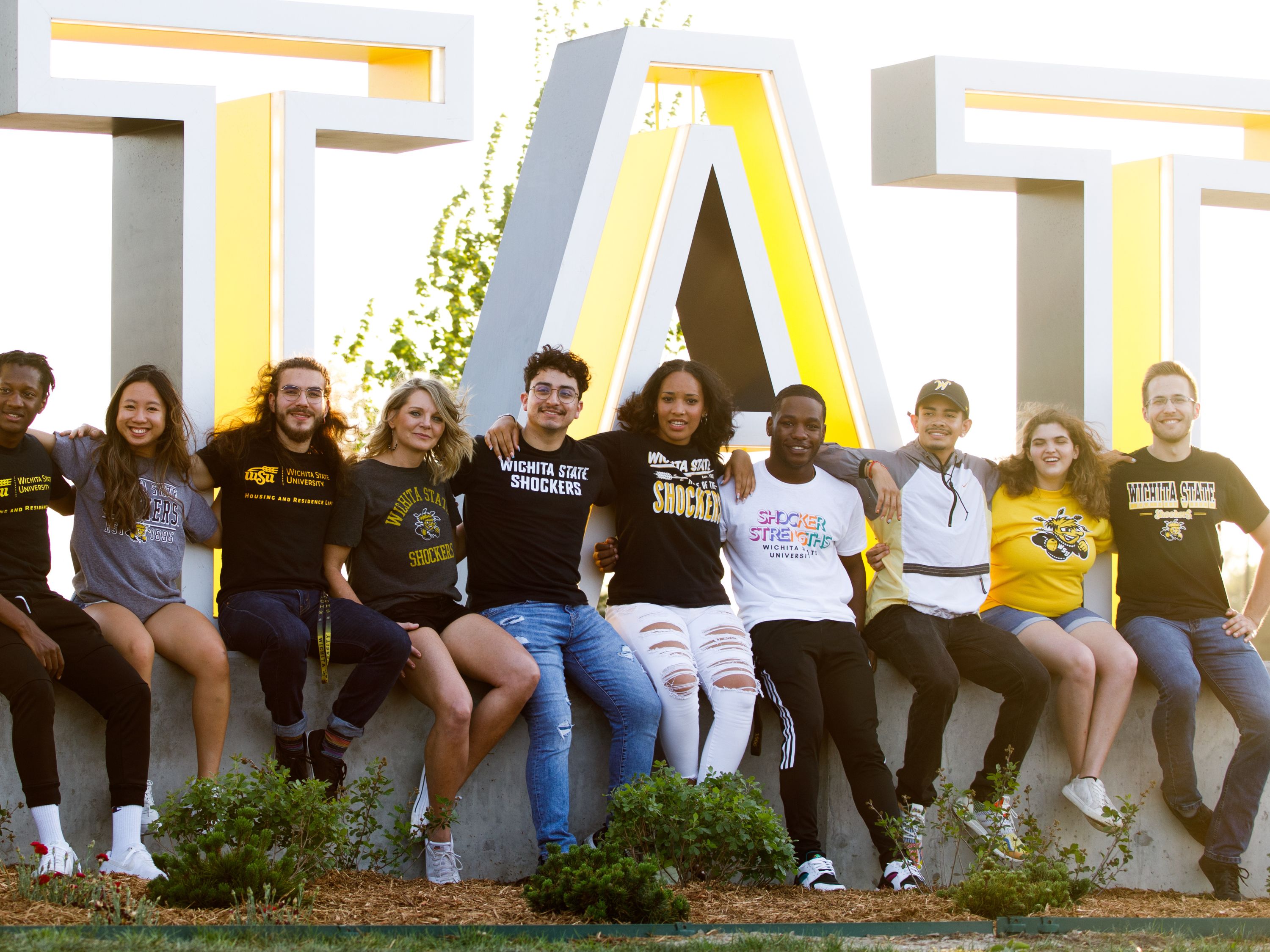 Students sitting on the Wichita State Sign
