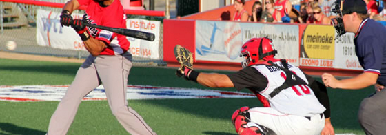 Photo of a batter swinging at the ball at a baseball game. 