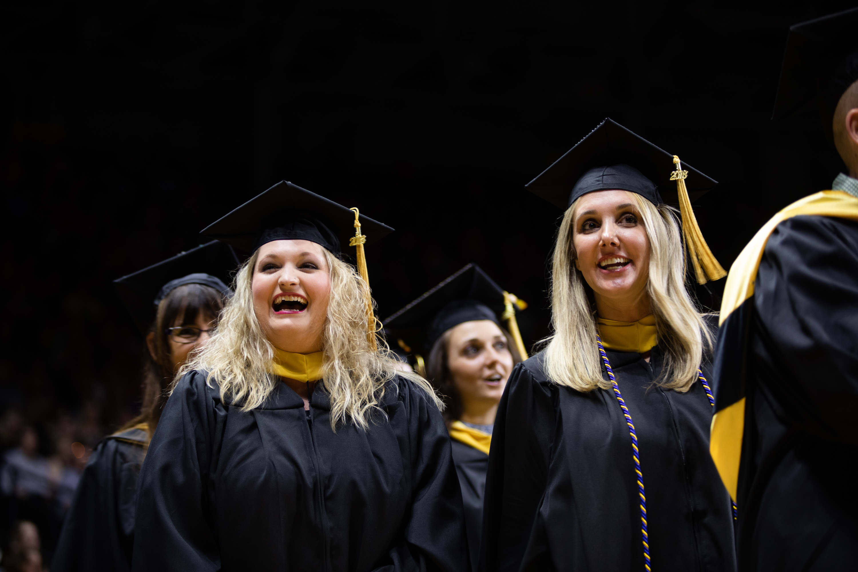 Students smiling in their caps and gowns as graduation day is about to commence. 