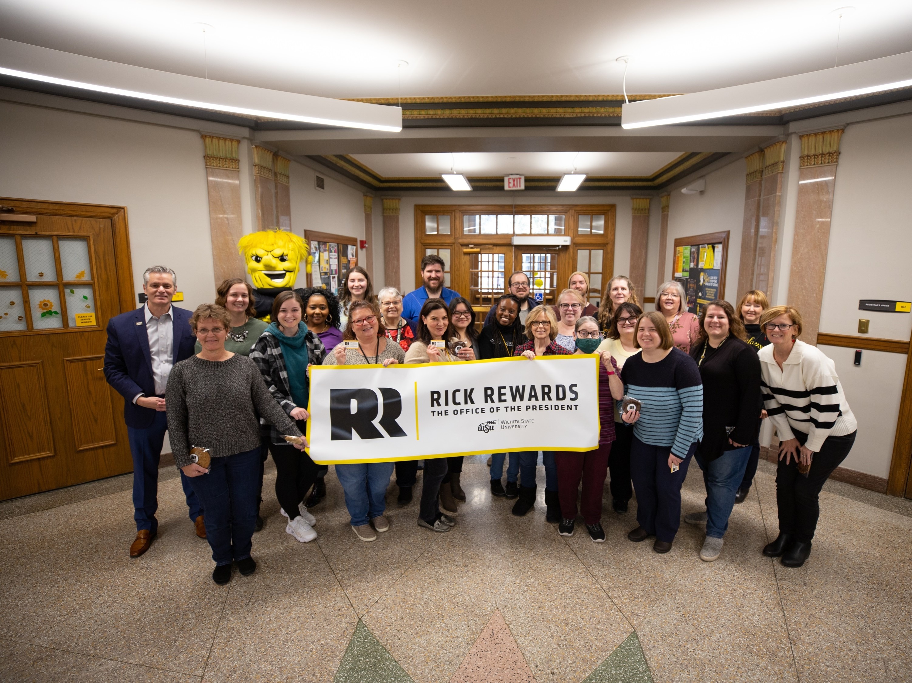 Photo of WSU President Dr. Rick Muma and various other employees presenting a "Rick Rewards" banner. 