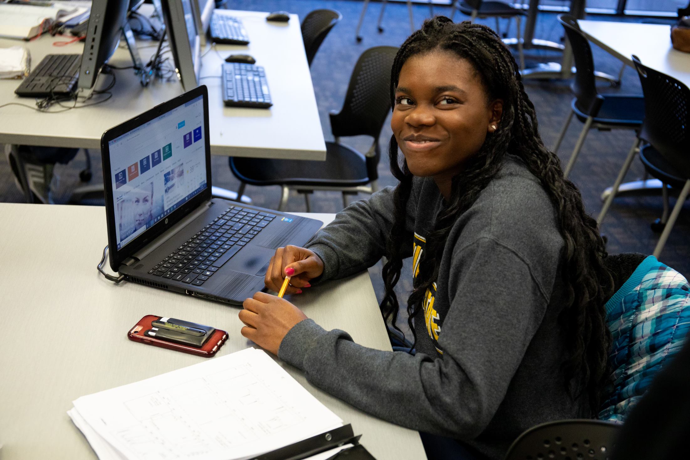 student at desk with laptop and studying materials