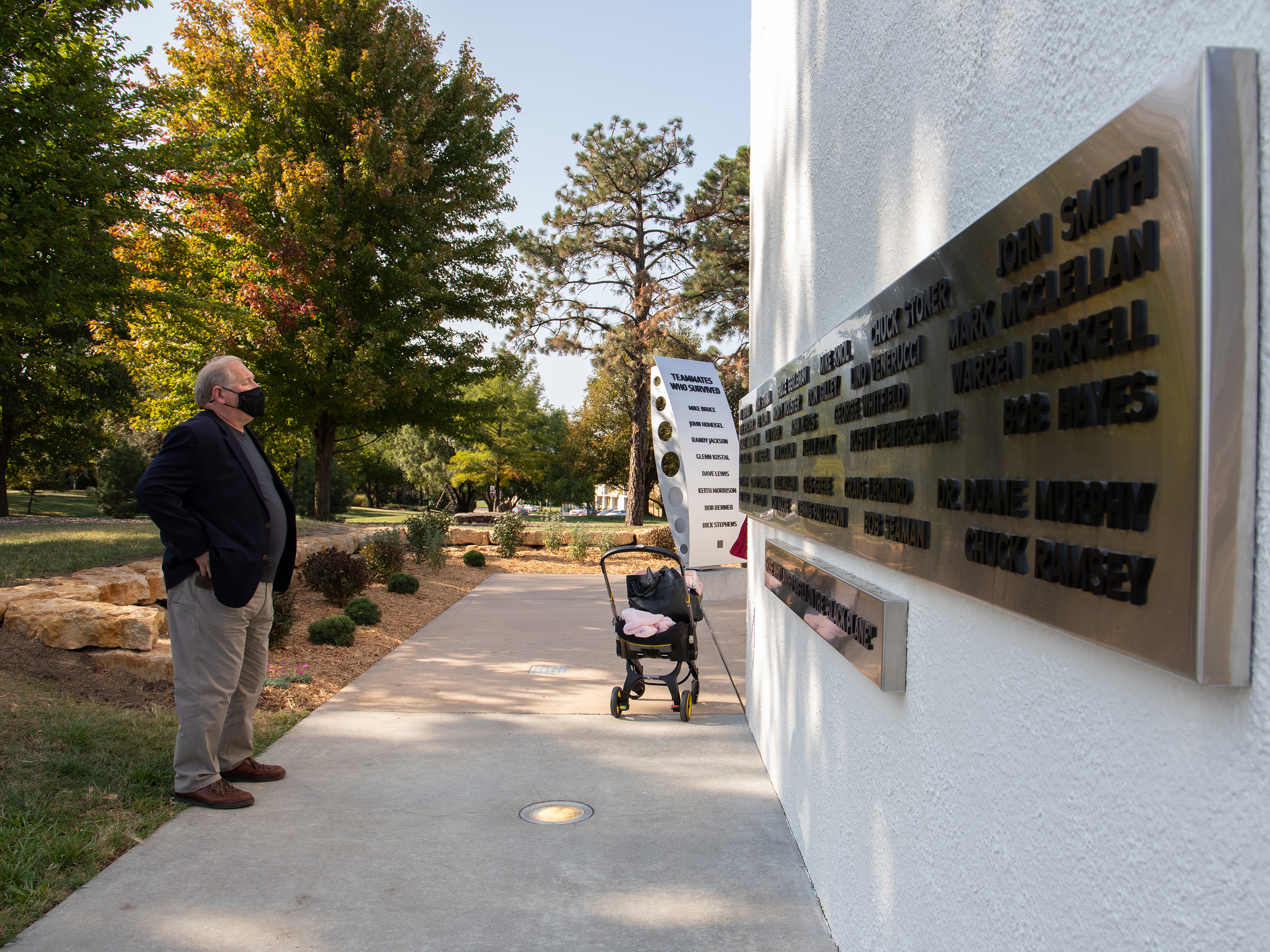 A man looks at names of black plane passengers on the south side of Memorial '70. In the background, the monument to the crash survivors is visible.