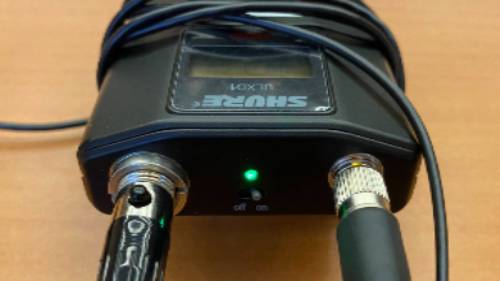 Lavalier microphone set to the on position initiates a green light when batteries are charged