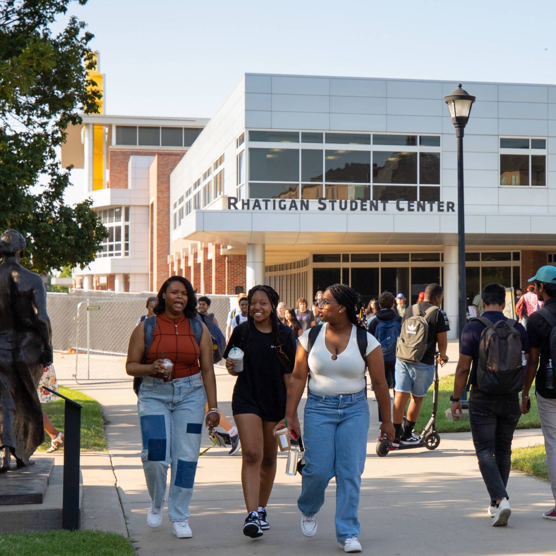 WSU students walking next to the sculpture called "Three Women Walking."