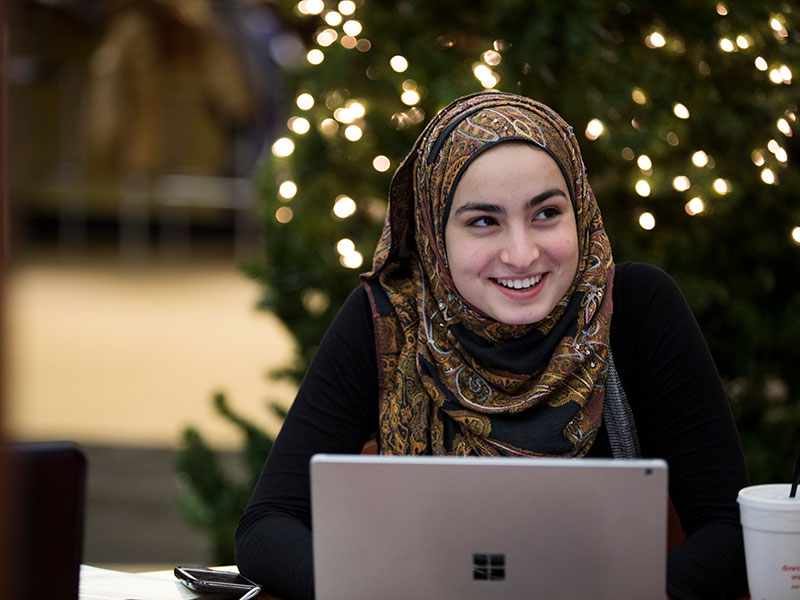 A student smiling as she types on her computer. 