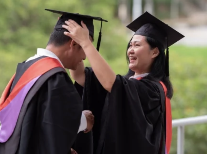 One student placing a graduation cap on another student