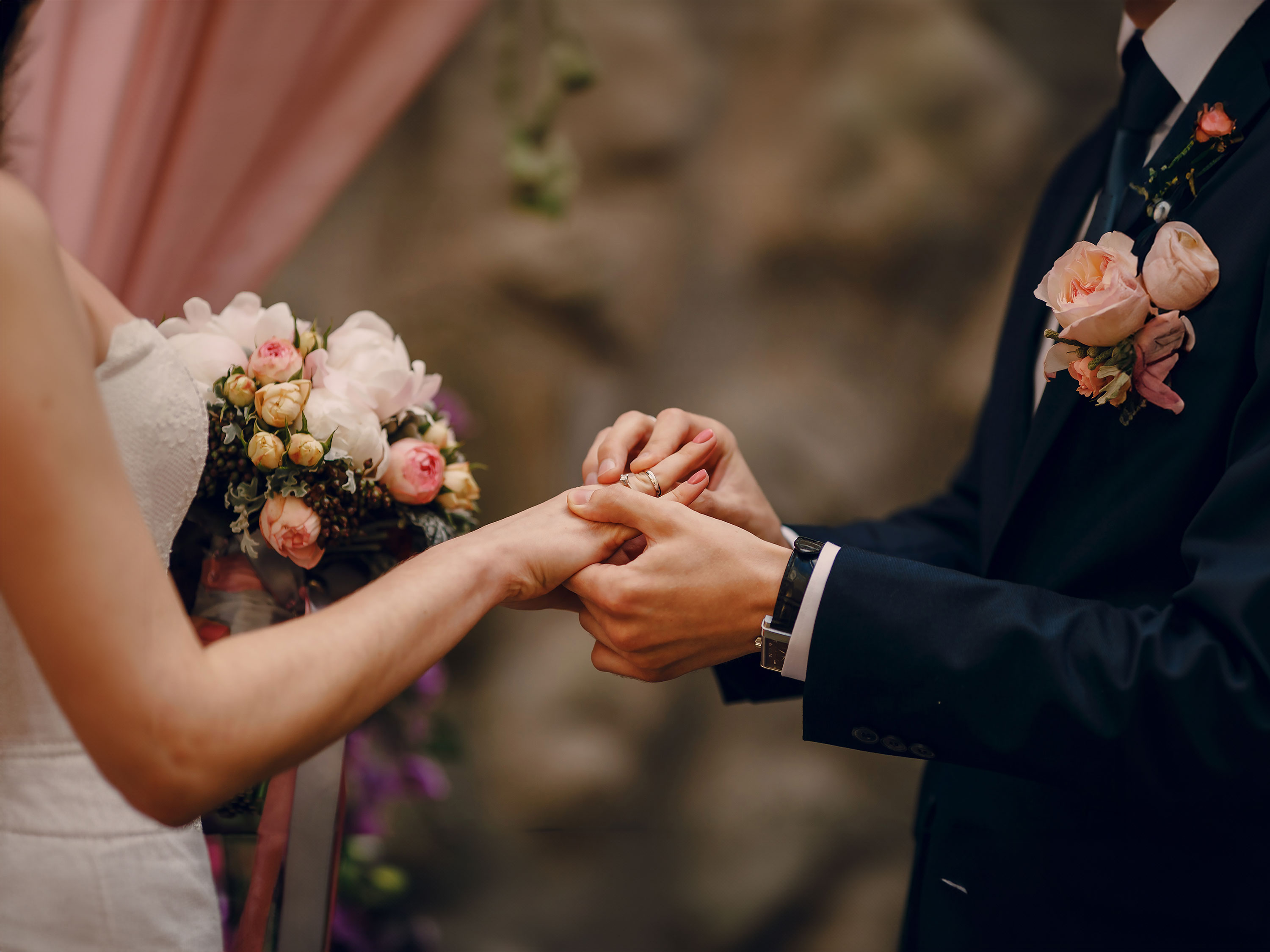 Groom putting a wedding ring on the bride.