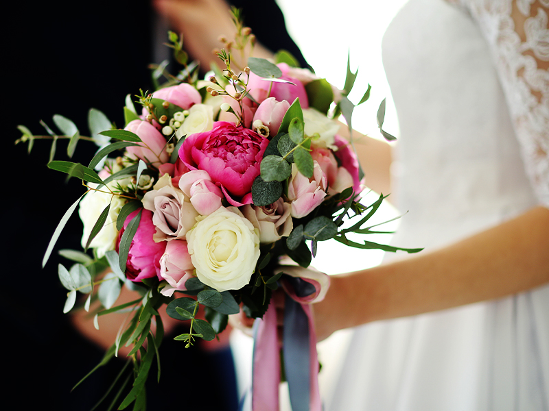 Newlywed couple holding a flower bouquet.