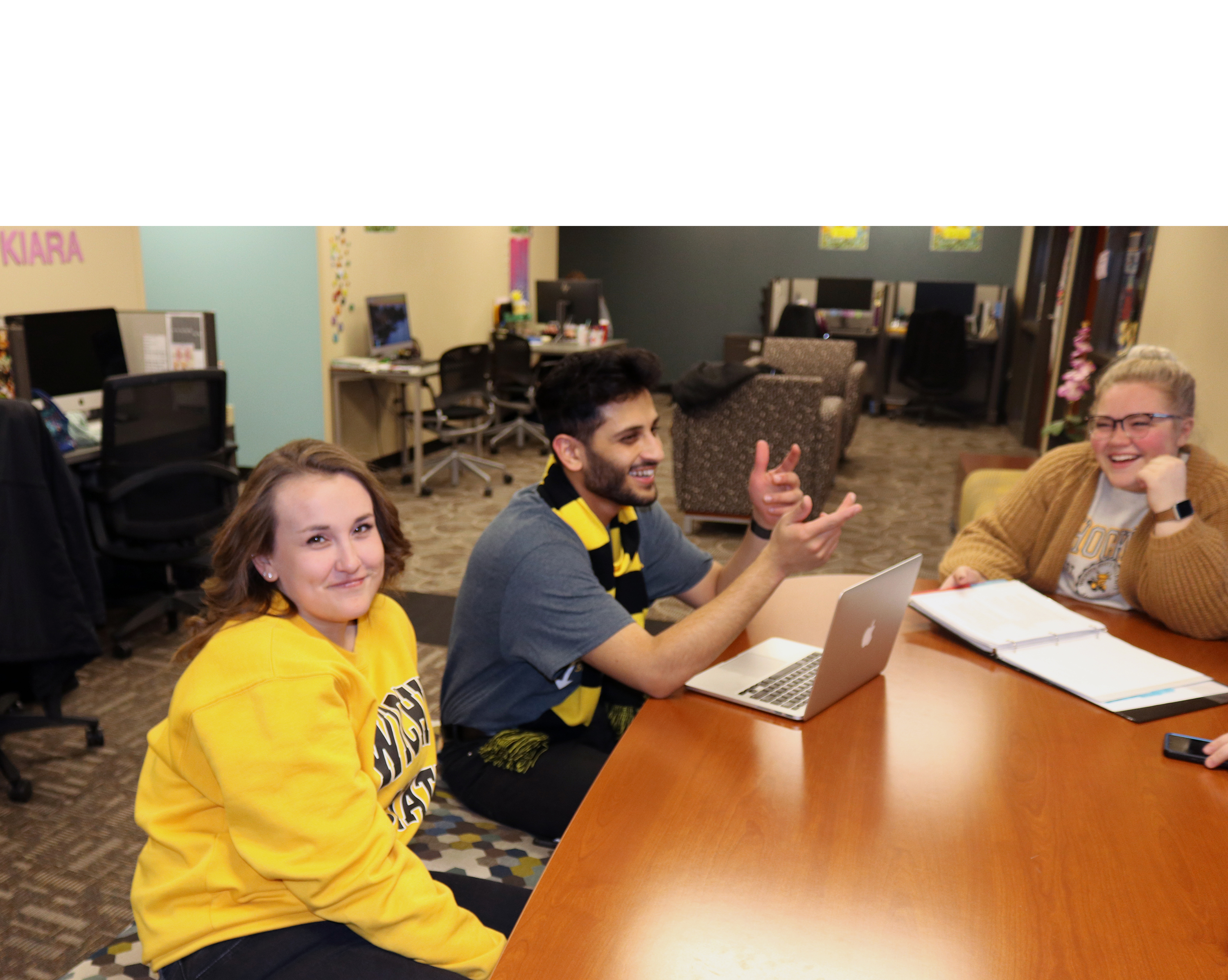 Graduate Assistants having a discussion at a table in Student Involvement.
