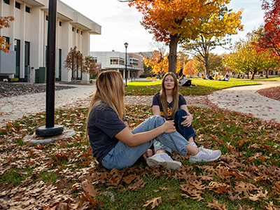 Students sitting outside under tree