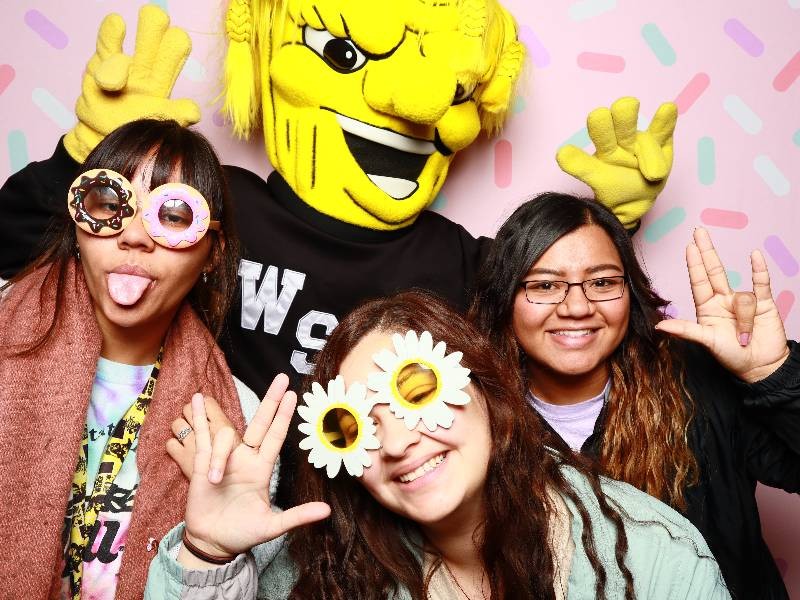 three students posing with Wichita State mascot, WuShock, at Wu's Birthday Bash