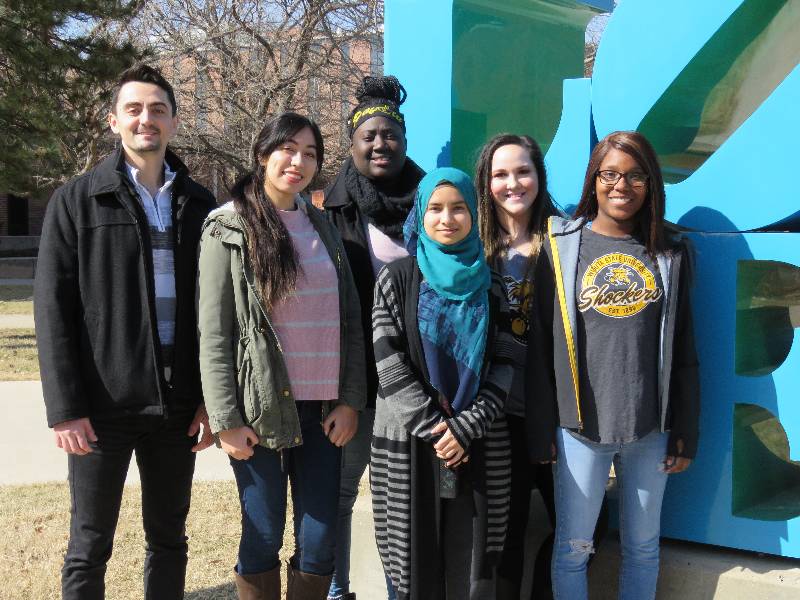 Six staff members in front of the love statue