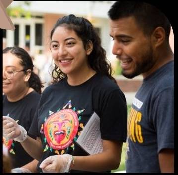 Photo of three smiling students at a campus event.