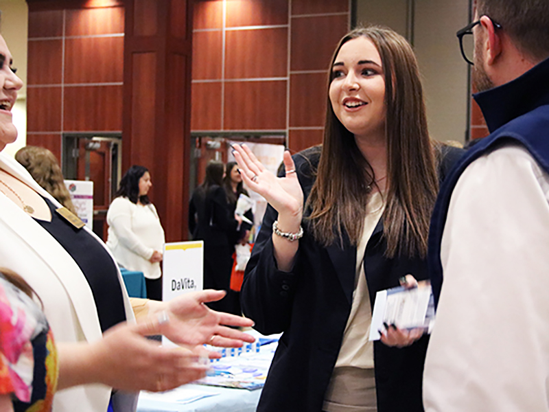 Student speaking with employers at a career fair.