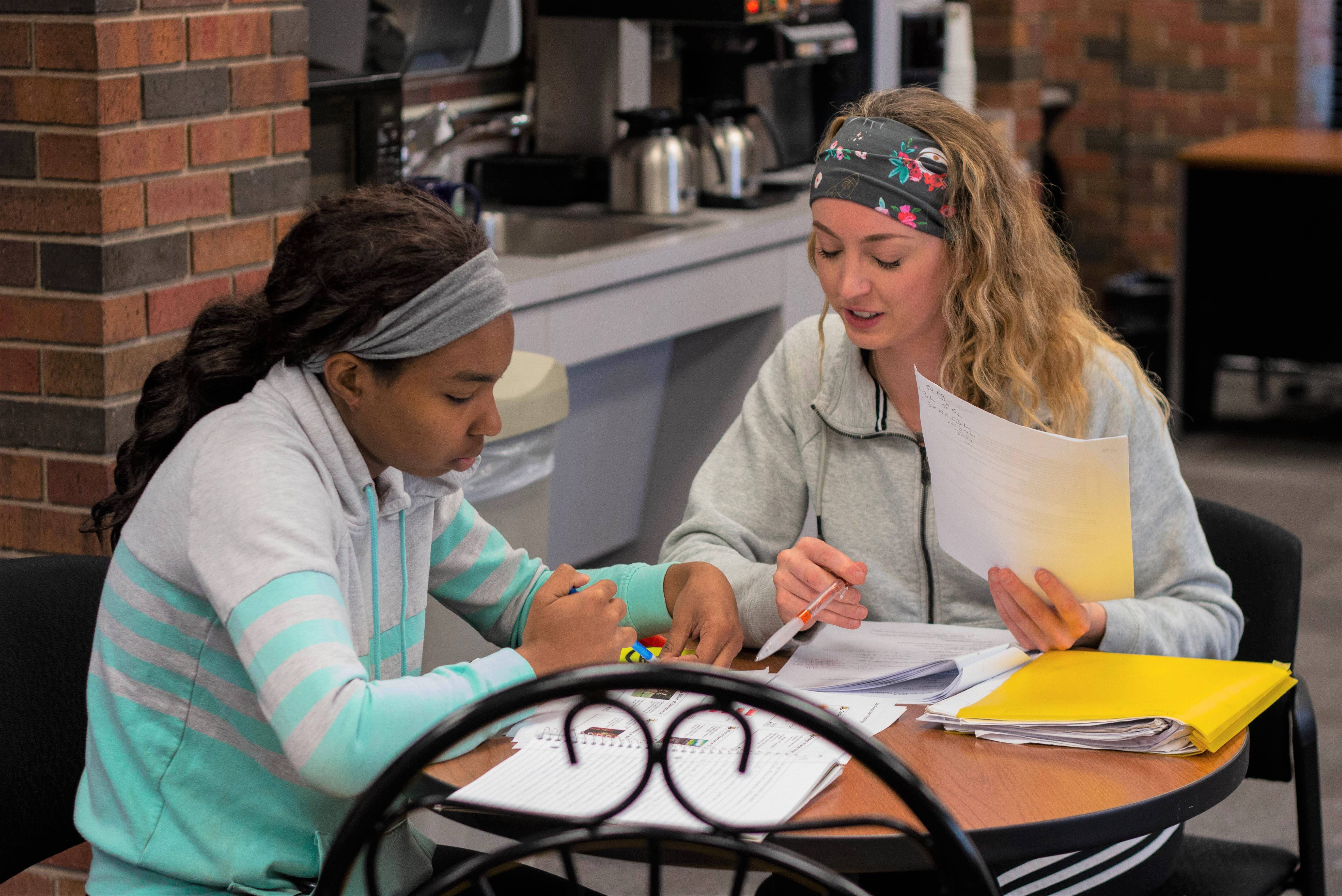 An SI Leader and a student seated around a table work on studies