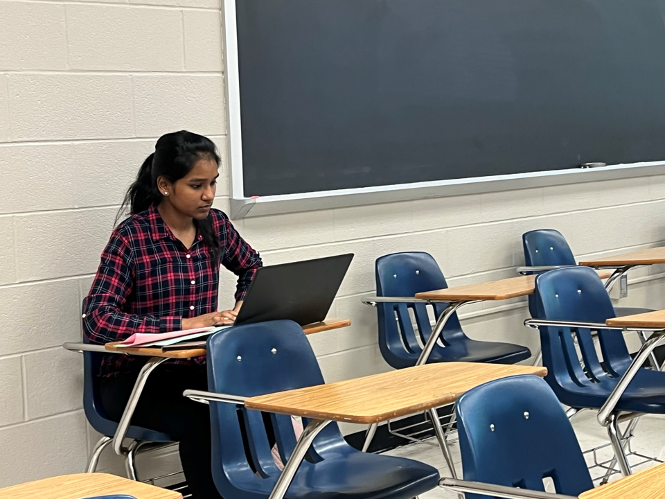 A student seated at a desk with a laptop.
